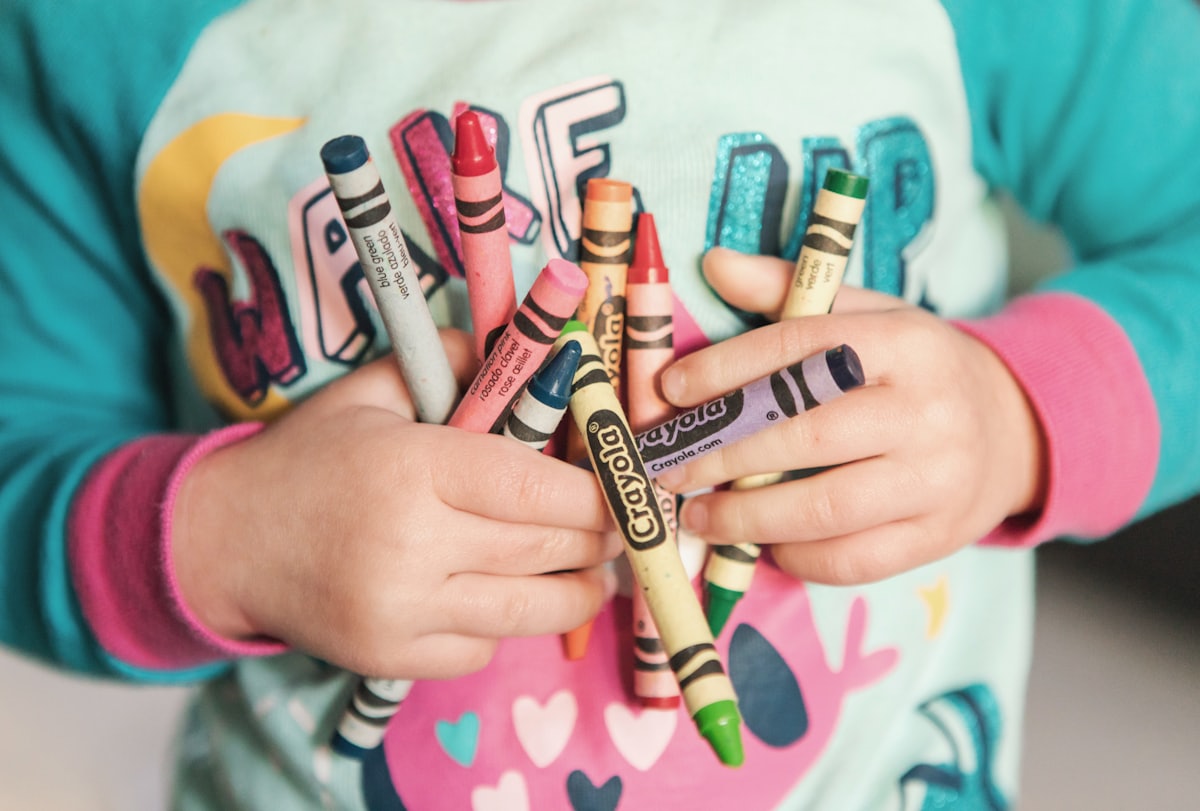 A child gripping a colorful bundle of crayons, ready to color a printable activity sheet